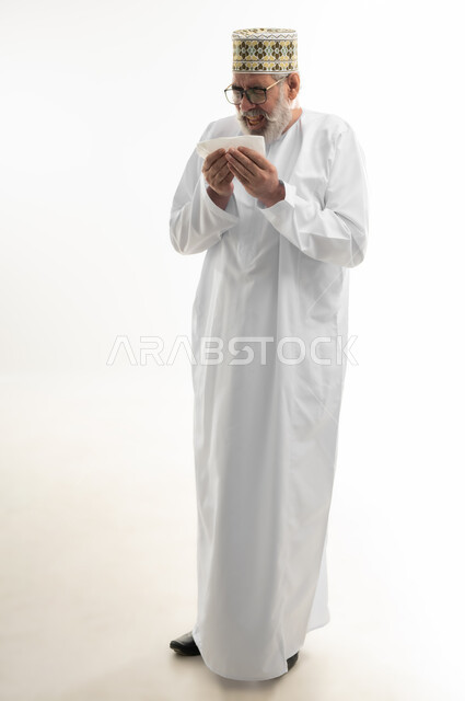 الإرهاق والتعب والحاجة للراحة، العطاس والكحه وأعراض الرشح، الإصابة بالزكام والانفلونزا، بورتريه لرجل شايب عربي خليجي عماني يرتدي الدشداشة والكمه العمانية يمسك المنديل الورقي بيده لمنع انتشار العدوى، ضرورة أخذ العلاج المناسب، الجسم بالطول الكامل، خلفية بيضاء