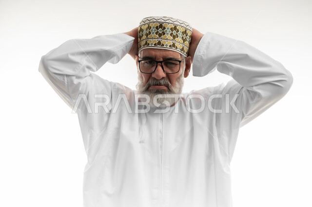 الأسف عل خسارة شيء ما ذو قيمة، خيبة الأمل والتعرض لخذلان وصدمة، الإحباط والحزن على ضياع الفرصة، بورتريه مقرب لرجل شايب عربي خليجي عماني يرتدي الدشداشة والكمه والنظارة الطبية يضع يديه خلف رأسه بتعابير الحسرة والندم، خلفية بيضاء