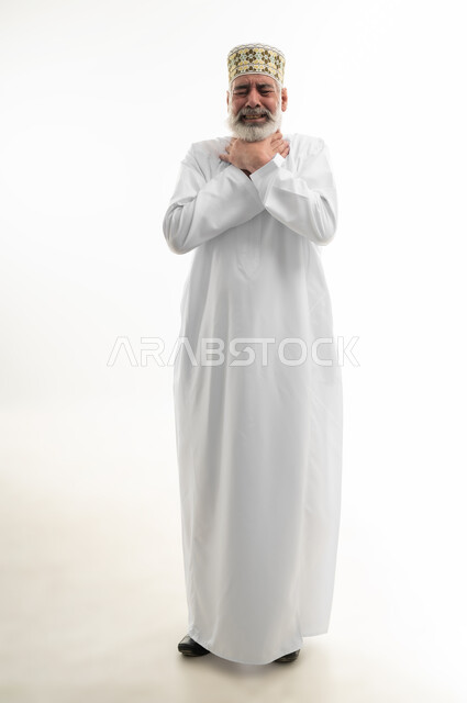 إيماءات الانزعاج الشديد والمعاناة، بورتريه لرجل كبير بالسن عربي خليجي عماني يرتدي الدشداشة والكمه يضع يديه حول عنقه في محاولة لخنق نفسه، الاختناق والشعور بضيق، قتل النفس للهرب من المشاكل والهموم والضغوطات المحيطة، الجسم بالطول الكامل، خلفية بيضاء