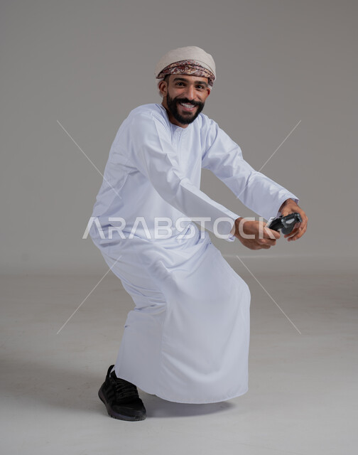 Interaction and integration with PlayStation games, entertaining electronic techniques, portrait of an Omani Arabian Gulf man wearing a dishdasha and turban holding a joystick, a fun and exciting entertainment experience on modern devices, gestures of victory and triumph, gray background