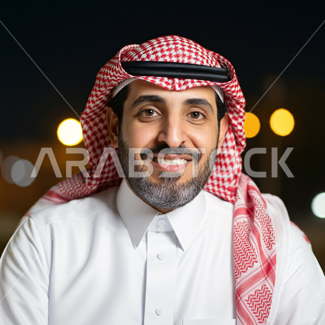 The concept of elegance and interest in appearance, a close-up image of a smiling Saudi Arabian Gulf man wearing the traditional thobe and shemagh looking at the camera with gestures of self-confidence and pleasure
