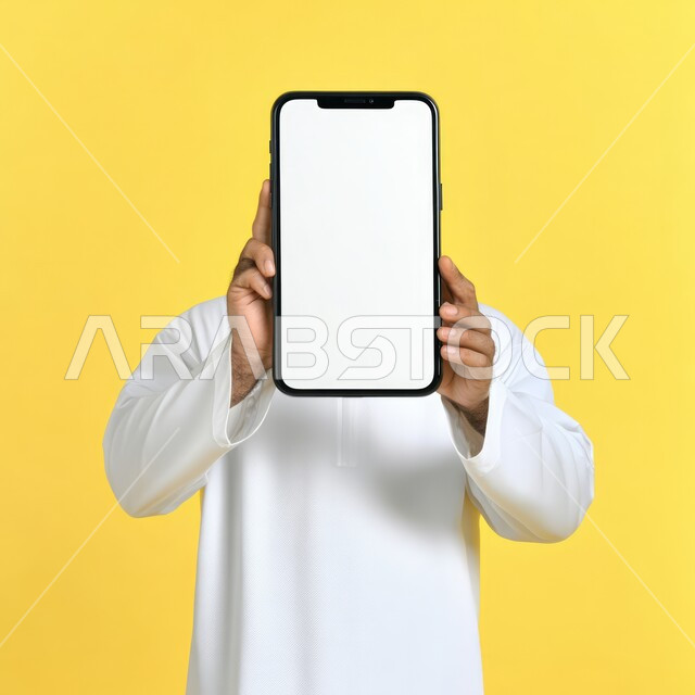  استخدام أجهزة التكنولوجيا الحديثة والمتطورة، بورتريه لرجل عربي خليجي سعودي يحمل هاتف محمول, عرض شاشة بيضاء فارغة عبر الجوال, متاجر تسوق الكترونية، خلفية صفراء