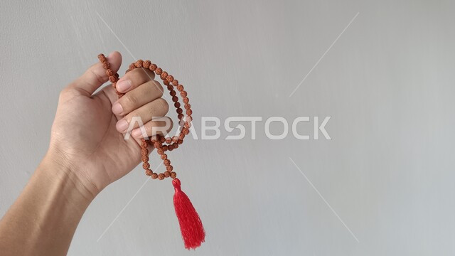 الطمأنينة بالتقرب إلى الله سبحانه، صورة مقربة ليد تمسك السبحة، التسبيح وذكر الله تعالى، الإستغفار والدعاء، العبادة والتقرب الى الله، إسلاميات وعبادة، خلفيه بيضاء