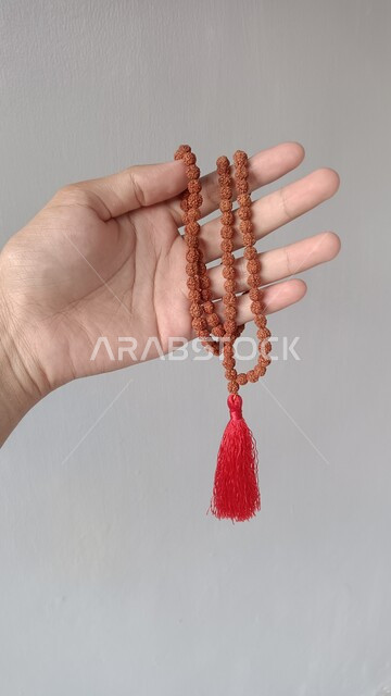 الطمأنينة بالتقرب إلى الله سبحانه، صورة مقربة ليد تمسك السبحة، التسبيح وذكر الله تعالى، الإستغفار والدعاء، العبادة والتقرب الى الله، إسلاميات وعبادة، خلفيه بيضاء