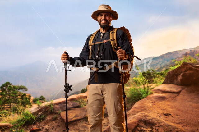 Hiking, mountain peaks and heights, recreational physical activities, camping tours and trips in Saudi Arabia, maintaining health and fitness, back view of a young Saudi Arabian Gulf man wearing a mountain climbing equipment bag
