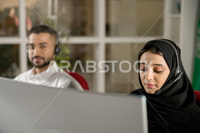موظفان عربيان خليجيان سعوديان يعملان في خدمة العملاء، موظف وموظفة يرتديان سماعة الاتصال، استعلامات واستفسارات، الاجابه على اسئلة العملاء، اجراء اتصال فيديو من خلال الحاسوب، متابعة وتطوير العمل
