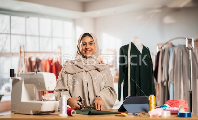 ورشة عمل تصميم أزياء, ممارسة مهنة الخياطة , مصممة أزياء عربية خليجية ترتدي العباءة الملونة والحجاب , حرف و مهن يدوية في المملكة، أعمال تقليدية شعبية, اتقان صنع الملابس السعودية