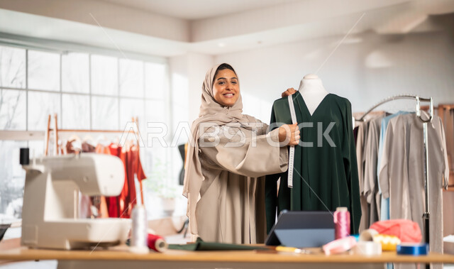 ورشة عمل تصميم أزياء, ممارسة مهنة الخياطة , مصممة أزياء عربية خليجية ترتدي العباءة الملونة والحجاب , حرف و مهن يدوية في المملكة، أعمال تقليدية شعبية, اتقان صنع الملابس السعودية