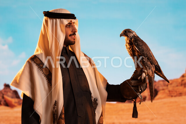 الفخر بالتراث السعودي العريق في تربية الطيور الجارحة الحرة، رمز القوة والتحدي وحدة البصر، فعاليات نادي الصقور في موسم الصيد السنوي في المملكة العربية السعودية، صورة لشاب عربي خليجي سعودي يقوم بترويض طائر الصقر في المحميات الطبيعة