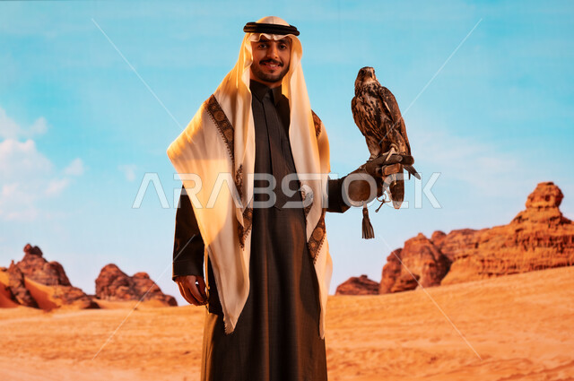فعاليات نادي الصقور في موسم الصيد السنوي في المملكة العربية السعودية، الفخر بالتراث السعودي العريق في تربية الطيور الجارحة الحرة، رمز القوة والتحدي وحدة البصر،  صورة لشاب عربي خليجي سعودي يقوم بترويض طائر الصقر في المحميات الطبيعة
