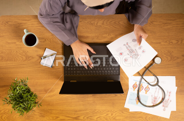 استخدام التقنيات الحديثة والمتطورة، الخدمات والأجهزة الطبية، مفهوم الطب والرعاية الصحية، دمج التكنولوجيا في الحياة العملية، بورتريه علوي عامودي لإمرأة عربية خليجية عمانية تستخدم الحاسوب المحمول وتحمل بيدها الأوراق لتشخيص الأمراض