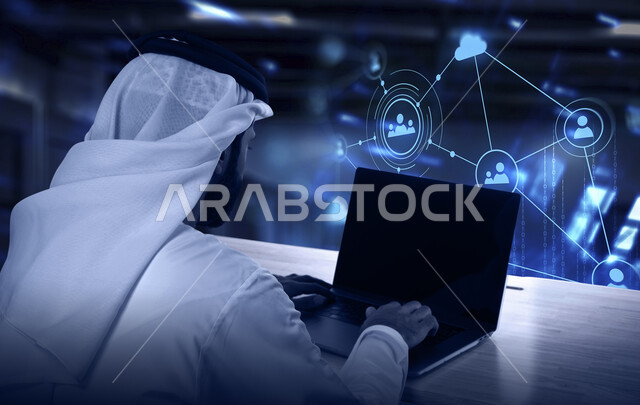 العناصر الهولوجرامية ثلاثية الابعاد، استخدام التقنيات والأجهزة الحديثة، صورة من الخلف لرجل عربي خليجي سعودي يرتدي الشماغ و الثوب التقليدي يعمل على جهاز اللابتوب المحمول، إنجاز مهام العمل عن بعد في المملكة العربية السعودية