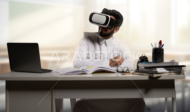 استخدام التقنيات والأجهزة الحديثة، نظام التعليم الذاتي، صورة مقربة لطالب عربي خليجي سعودي يرتدي الثوب التقليدي ونظارة في آر يستخدم جهاز اللابتوب المحمول، تطبيقات و برامج التعلم الالكتروني في مدارس المملكة العربية السعودية