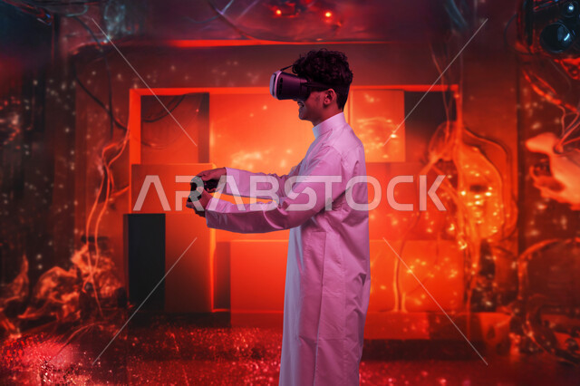 تعابير الاندماج والتفاعل، محاكاة العالم الخيالي، صورة من الجانب لشاب عربي سعودي خليجي يرتدي الثوب التقليدي ونظارات الواقع الافتراضي يحمل عصا التحكم يقوم باللعب في ألعاب الفيديو بإيماءات الحماس، اجهزة وتقنيات حديثة