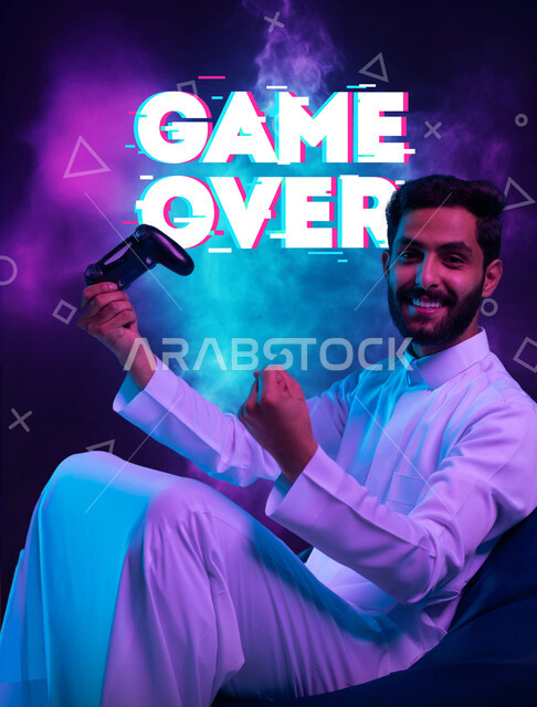 اجهزة وتقنيات الكترونية حديثة ترفيهيه, تعابير الاندماج والتفاعل، بورتريه لشاب عربي سعودي خليجي يرتدي الثوب التقليدي يجلس على كرسي مريح يحمل بيده عصا التحكم يقوم باللعب في ألعاب الفيديو ينظر الى الكاميرا بإيماءات الحماس والسرور، خلفية ملونة