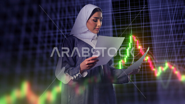 Promoting the concept of digital and technological development in Saudi society, using modern technologies, a close-up image of a veiled Saudi Arabian Gulf woman wearing an abaya holding papers reviewing data standing in front of electronic screens, illuminated holographic lines
