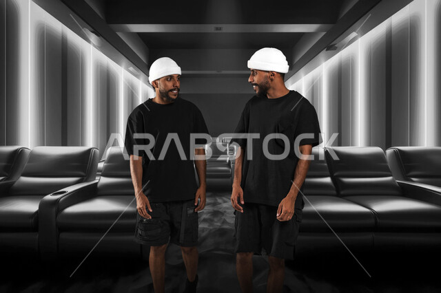 Feelings of love and friendship between brothers, enjoying a fun time, gestures of joy and happiness, two young Saudi Arabian Gulf twins wearing casual clothes and white hats looking at each other and exchanging conversations, full body image