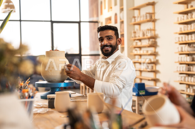 مناسبات واعياد وطنية, الصناعات التشكيلية اليدوية، شاب عربي خليجي سعودي يرتدي الثوب التقليدي يقوم برسم الزخرفة على جرة كبيرة, منحوتات وزخارف وأعمال فنية, حرف ومهن شعبية تراثية قديمة، تأسيس الدولة السعودية 1727 م, ذكرى اليوم الوطني السعودي 23 سبتمبر
