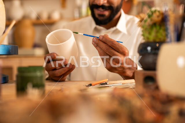 مناسبات واعياد وطنية, الصناعات التشكيلية اليدوية، شاب عربي خليجي سعودي يرتدي الثوب التقليدي يقوم بالرسم على السيراميك, منحوتات وزخارف وأعمال فنية, حرف ومهن شعبية تراثية قديمة، تأسيس الدولة السعودية 1727 م, ذكرى اليوم الوطني السعودي 23 سبتمبر