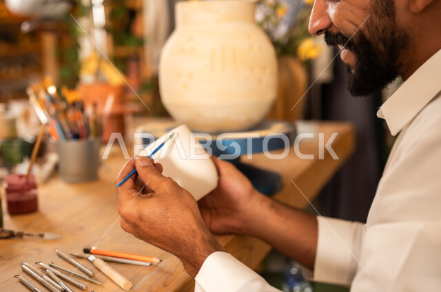 مناسبات واعياد وطنية, الصناعات التشكيلية اليدوية، شاب عربي خليجي سعودي يرتدي الثوب التقليدي يقوم بالرسم على السيراميك, منحوتات وزخارف وأعمال فنية, حرف ومهن شعبية تراثية قديمة، تأسيس الدولة السعودية 1727 م, ذكرى اليوم الوطني السعودي 23 سبتمبر