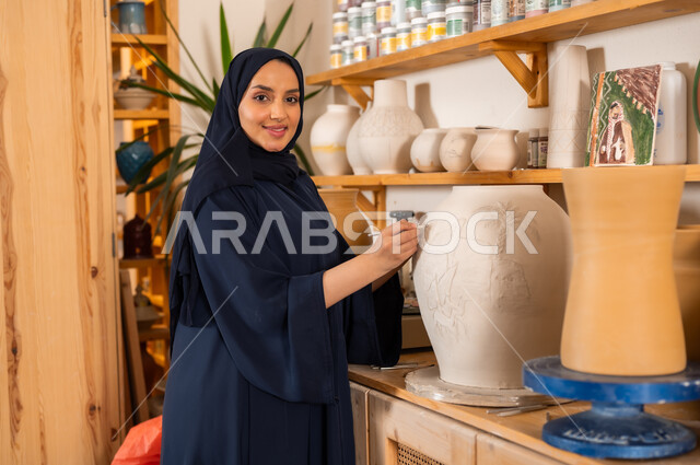  حرف ومهن شعبية تراثية قديمة, الصناعات التشكيلية اليدوية, امرأة عربية خليجية سعودية محجبة ترتدي العباءة السوداء تقوم برسم الزخرفة على جرة كبيرة, تأسيس الدولة السعودية 1727 م, ذكرى اليوم الوطني السعودي 23 سبتمبر, مناسبات واعياد وطنية