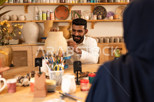 اعمال يديويه سعوديه, الأواني والمنتجات الفخارية المصنوعة من الطين, فن الرسم والتلوين على التحف, تأسيس الدولة السعودية 1727 م, ذكرى اليوم الوطني السعودي23 سبتمبر, شاب عربي خليجي يرتدي الثوب التقليدي يقوم بالرسم على الفخار