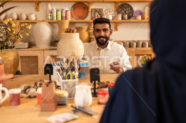 اعمال يديويه سعوديه, الأواني والمنتجات الفخارية المصنوعة من الطين, فن الرسم والتلوين على التحف, تأسيس الدولة السعودية 1727 م, ذكرى اليوم الوطني السعودي23 سبتمبر, شاب عربي خليجي يرتدي الثوب التقليدي يقوم بالرسم على الفخار