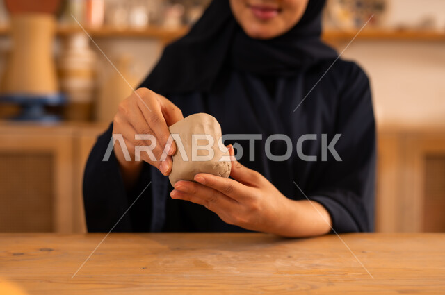 الصناعات التشكيلية اليدوية, حرف ومهن شعبية تراثية قديمة، امرأة عربية خليجية سعودية محجبة ترتدي العباءة السوداء تعمل بعجينة الفخار, تأسيس الدولة السعودية 1727 م, ذكرى اليوم الوطني السعودي 23 سبتمبر, مناسبات واعياد وطنية