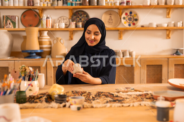 Handicrafts, traditional folk crafts and professions, a veiled Saudi Arabian Gulf woman wearing a black abaya working with pottery dough, the founding of the Saudi state in 1727 AD, the anniversary of Saudi National Day September 23, national occasions and holidays