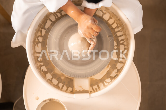Popular crafts and handicrafts from the ancient Saudi heritage, working in the ceramics industry, ceramic pots made of clay, making decorated pottery jars, a close-up of the hands of a Saudi Arabian Gulf woman making pottery