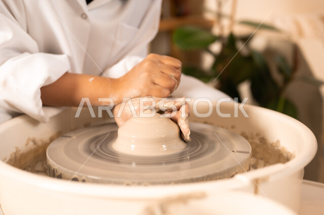 Popular crafts and handicrafts from the ancient Saudi heritage, working in the ceramics industry, ceramic pots made of clay, making decorated pottery jars, a close-up of the hands of a Saudi Arabian Gulf woman making pottery