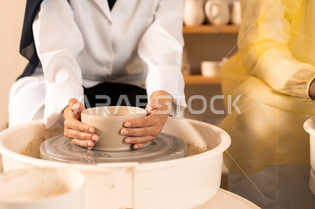 حرف وصناعات يدوية شعبية من التراث السعودي العريق، العمل في صناعة الخزفيات, اواني خزفية مصنوعة من الطين، صنع الجرار الفخارية المزخرفة، صورة مقربة لايدي امرأة عربية سعودية خليجية تقوم بصناعة الفخار