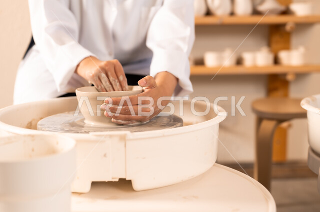 Popular crafts and handicrafts from the ancient Saudi heritage, working in the ceramics industry, ceramic pots made of clay, making decorated pottery jars, a close-up of the hands of a Saudi Arabian Gulf woman making pottery
