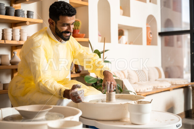 محترف عربي سعودي خليجي يعمل في ورشة الاعمال الفنية، ممارسة مهارة صنع الفخار، احتراف تلوين الخزف والفخاريات، أعمال يدوية سعودية