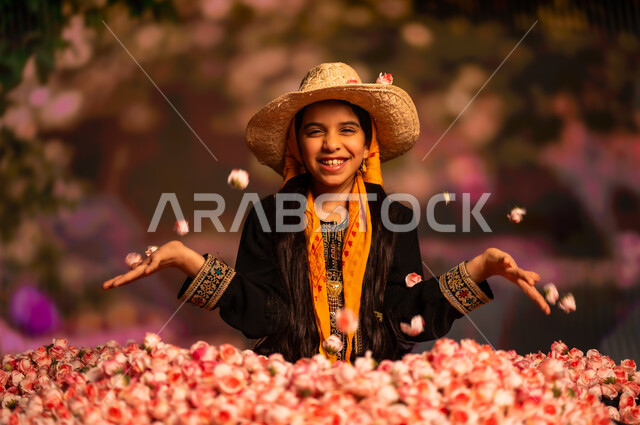  اليوم الوطني السعودي 23سبتمبر، الاحتفال بالمناسبات والأعياد الوطنية، الجلوس داخل كومه من الازهار الوردية، صورة مقربة لفتاة عربية خليجية سعودي ترتدي السدرة والشيلة  تنظر إلى الكاميرا بايماءات السعادة والسرور، يوم بدينا 1727 م