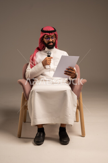 القيام بالحوارات والنقاشات، قراءة الملاحظات والمعلومات، بورتريه لرجل عربي خليجي سعودي يرتدي الثوب التقليدي والشماغ يجلس على الكرسي يحمل بيده مجموعة من الأوراق ومكبر الصوت يقوم بإلقاء الخطابات، إعداد وتحضير أفكار الخطاب بشكل مسبق، خلفية رمادية