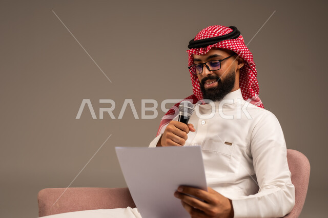 إعداد وتحضير أفكار الخطاب بشكل مسبق، القيام بالحوارات والنقاشات، بورتريه مقرب لرجل عربي خليجي سعودي يرتدي الثوب التقليدي والشماغ يجلس على الكرسي يحمل بيده مجموعة من الأوراق ومكبر الصوت يقوم بإلقاء الخطابات، قراءة الملاحظات والمعلومات، خلفية رمادية