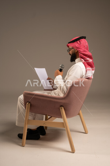 إعداد وتحضير أفكار الخطاب بشكل مسبق، القيام بالحوارات والنقاشات، بورتريه من الجانب لرجل عربي خليجي سعودي يرتدي الثوب التقليدي والشماغ يجلس على الكرسي يحمل بيده مجموعة من الأوراق ومكبر الصوت يقوم بإلقاء الخطابات، قراءة الملاحظات والمعلومات، خلفية رمادية