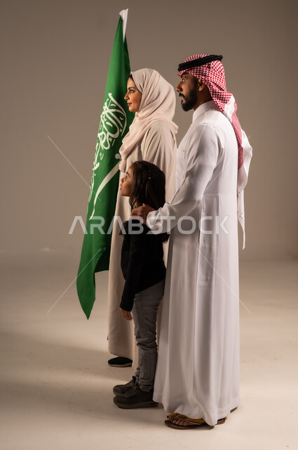 Saudi National Day Remembrance, Saudi National Holidays and Occasions, Family Atmosphere Full of Love, Portrait of a Happy Saudi Arabian Gulf Family Holding the Saudi Flag with Love and Pride, Celebrating Flag Day March 11, Saudi National Day 8 Rabi' al-Awwal, Grey Background