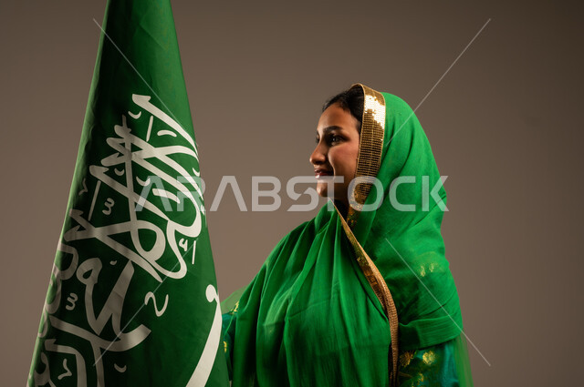 المشاركة بالأعياد الوطنية، اليوم الوطني السعودي، بورتريه لامرأة عربية خليجية سعودية محجبة  ترتدي الشيلة والبشت وترفع علم السعودية بايماءات الفخر والاعتزاز بالوطن، يوم العلم السعودي 11 مارس، العيد الوطني 23 سبتمبر، خلفية بيج
