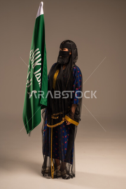  ذكرى تأسيس الدولة السعودية الأولى 22 فبراير، يوم بدينا 1727 م، بورتريه لإمرأة عربية خليجية سعودية ترتدي زي المنطقة الوسطى وتمسك بيدها علم التأسيس, الاعتزاز بالبلد والانتماء اليه، الجسم بالطول الكامل، خلفية بيج