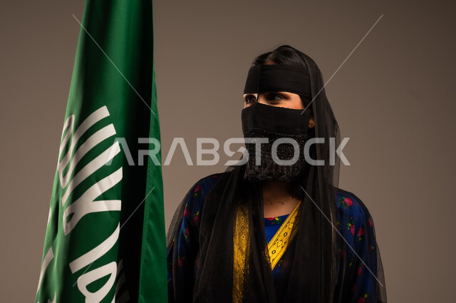 يوم بدينا 1727 م، ذكرى تأسيس الدولة السعودية الأولى 22 فبراير، اليوم الوطني السعودي، بورتريه لإمرأة عربية خليجية سعودية ترتدي زي المنطقة الوسطى وتمسك بيدها علم التأسيس, الاعتزاز بالبلد والانتماء اليه، خلفية بيج