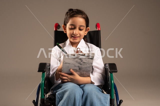الطموحات و الأهداف المستقبلية في العمل في العيادات والمشافي، تدوين وتسجيل معلومات وبيانات المرضى، تحديد مهنة المستقبل منذ الصغر، بورتريه لفتاة عربية خليجية سعودية من ذوي الاحتياجات الخاصة ترتدي زي ممرضة تجلس على كرسي متحرك تمسك بيدها ملف ملاحظات، خلفية رمادية