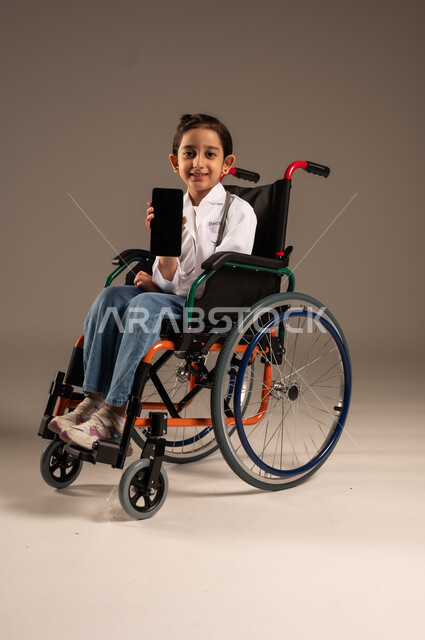 عرض شاشة سوداء فارغة عبر الهاتف المحمول، الطموحات والأهداف المستقبلية في العمل في العيادات والمشافي، استخدام الأجهزة التقنية الحديثة، بورتريه لفتاة عربية خليجية سعودية من ذوي الاحتياجات الخاصة ترتدي زي ممرضة تجلس على كرسي متحرك، خلفية رمادية