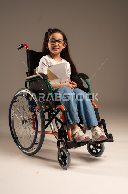 استغلال أوقات الفراغ بالأنشطة التعليمية، بورتريه لفتاة عربية خليجية سعودية من ذوي الاحتياجات الخاصة ترتدي الزي الكاجوال تجلس على كرسي متحرك تقوم بالمطالعة وقراءة الكتب المفيده،  تنمية المهارات الفنية والذهنية، مراجعة الدروس اليومية، خلفية رمادية