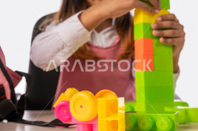 تلميذة عربية خليجية سعودية ترتدي الزي المدرسي ،مستمتعة بلعبة تركيب المكعبات (الليغو) ، تعزيز المهارات الفكرية ، القدرة على الابتكار والابداع ، دمج الالعاب مع المناهج التعليمية، التعليم في المملكة العربية السعودية