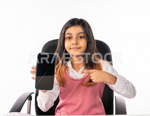 A Saudi Arabian Gulf schoolgirl wearing a school uniform, using a mobile phone, e-learning, remote study, following up on lessons and assignments online, new semester, education in Saudi Arabia, white background