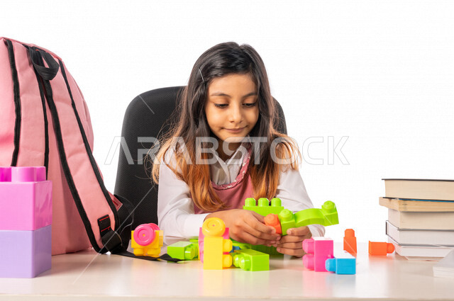 تلميذة عربية خليجية سعودية ترتدي الزي المدرسي ،مستمتعة بلعبة تركيب المكعبات (الليغو) ، تعزيز المهارات الفكرية ، القدرة على الابتكار والابداع ، دمج الالعاب مع المناهج التعليمية، التعليم في المملكة العربية السعودية