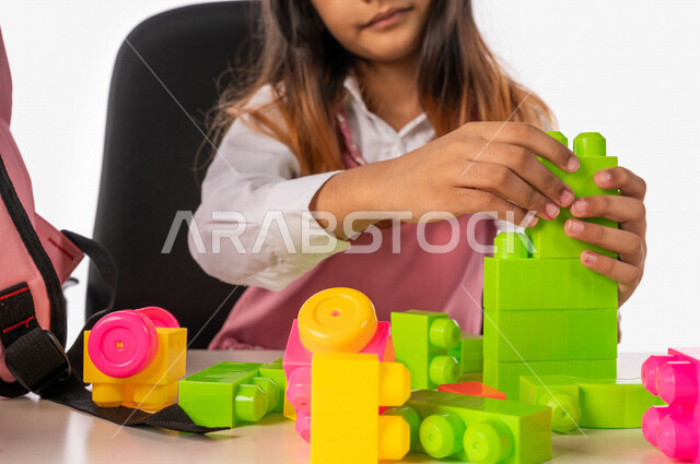 تلميذة عربية خليجية سعودية ترتدي الزي المدرسي ،مستمتعة بلعبة تركيب المكعبات (الليغو) ، تعزيز المهارات الفكرية ، القدرة على الابتكار والابداع ، دمج الالعاب مع المناهج التعليمية، التعليم في المملكة العربية السعودية
