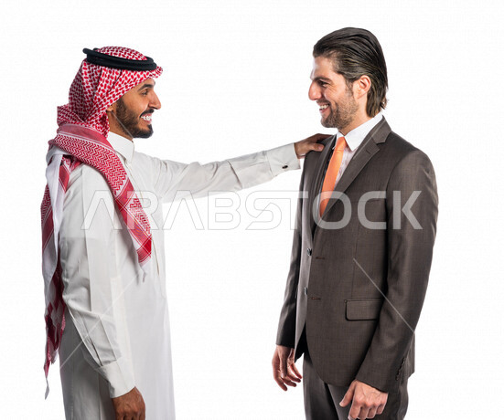 بورتريه لرجل عربي سعودي خليجي يضع يده على كتف الرجل الأجنبي بالبدلة الرسمية، يبتسمان إبتسامة هوليود ، بإيماءات الوجه واليدين المختلفة تدل على السعادة ، خلفية بيضاء ، الإتفاق والشراكة على الأعمال والمشاريع التجارية، شركاء العمل